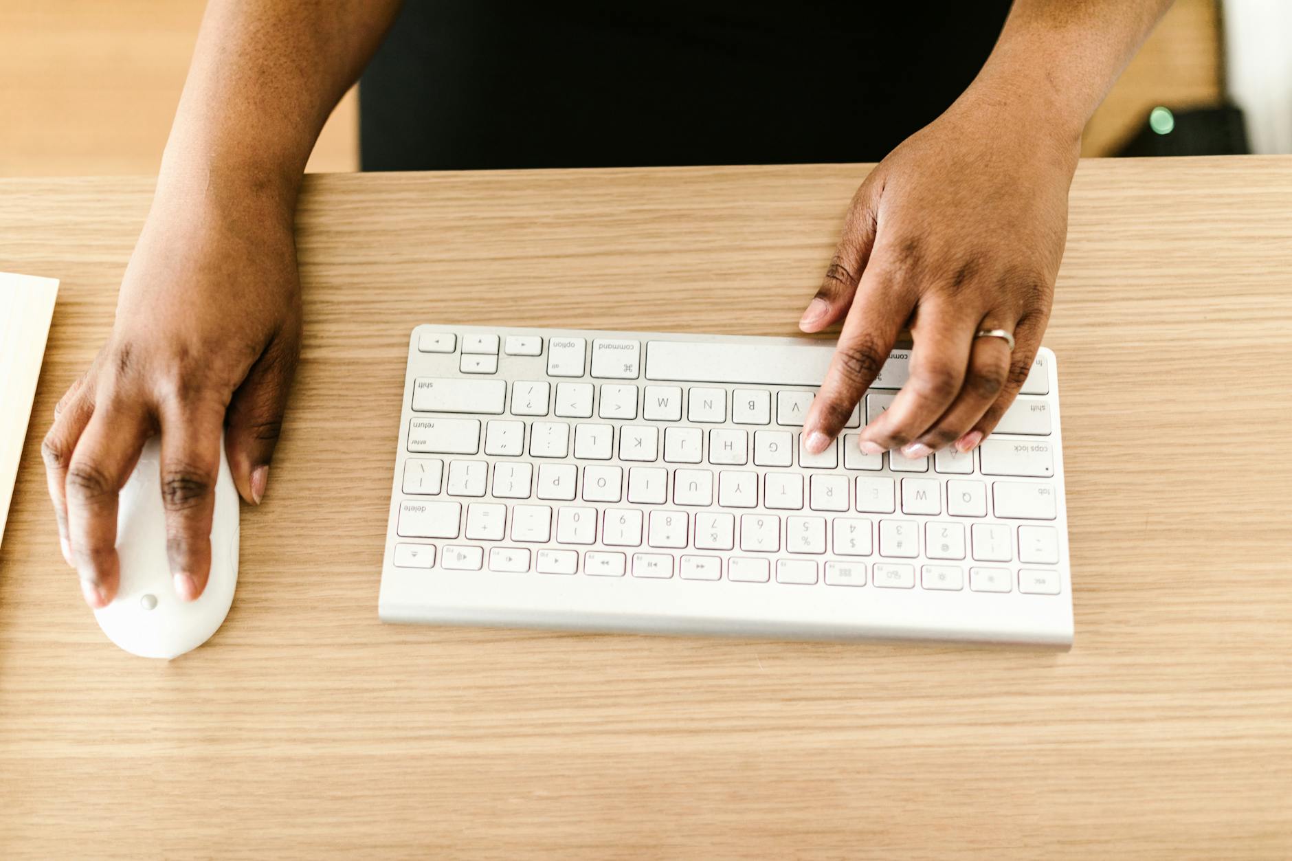 photo of a person holding a white computer mouse while typing